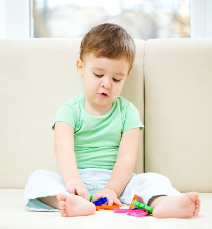 Cute little boy is playing while sitting on couchの写真素材