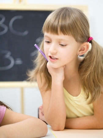 Cute little girl is writing using a pen in preschoolの写真素材