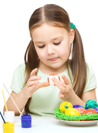 Little girl is painting eggs preparing for Easter, isolated over whiteの写真素材