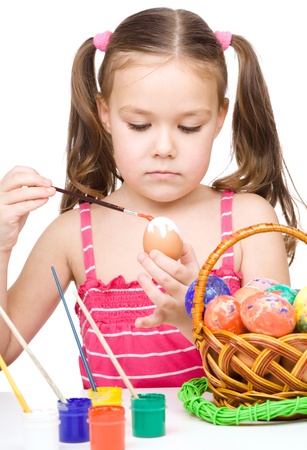 Little girl is painting eggs preparing for Easter, isolated over whiteの写真素材