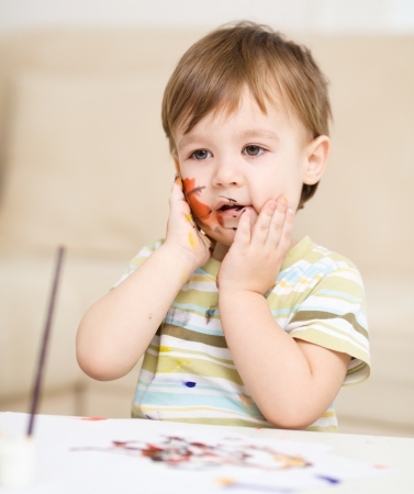 Portrait of a cute little boy messily playing with paintsの写真素材