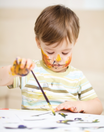 Portrait of a cute little boy playing with paintsの写真素材