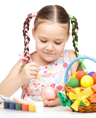 Little girl is painting eggs preparing for Easter, isolated over whiteの写真素材