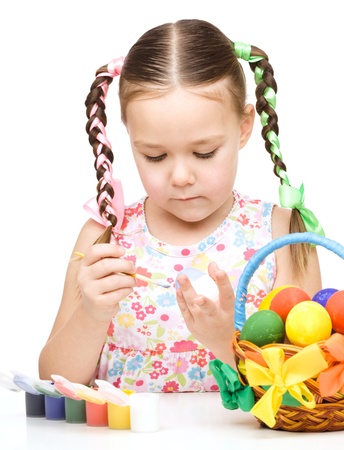 Little girl is painting eggs preparing for Easter, isolated over whiteの写真素材