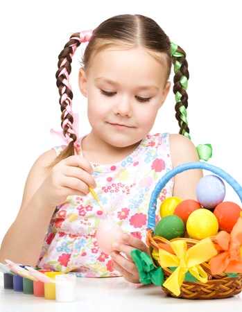 Little girl is painting eggs preparing for Easter, isolated over whiteの写真素材