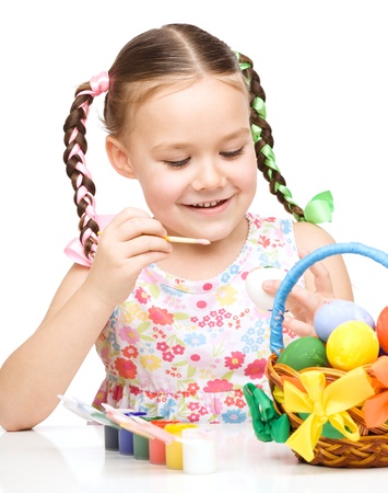 Little girl preparing eggs for Easter, isolated over whiteの写真素材