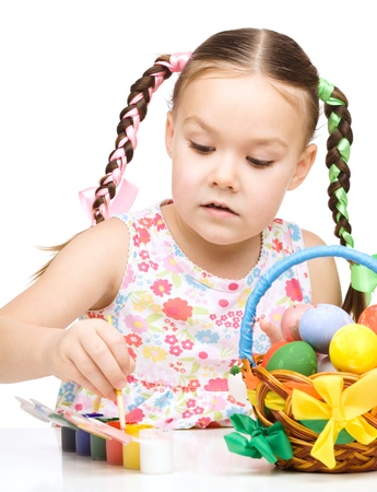 Little girl is painting eggs preparing for Easter, isolated over whiteの写真素材