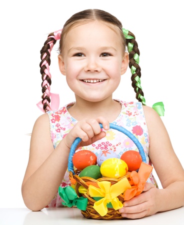 Little girl with basket full of colorful eggs preparing for Easter, isolated over whiteの写真素材
