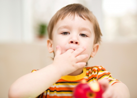 Little boy is eating red appleの写真素材