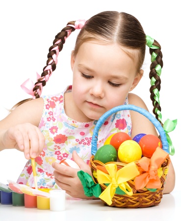 Little girl is painting eggs preparing for Easter, isolated over whiteの写真素材