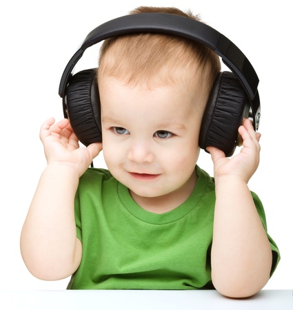 Cute little boy enjoying music using headphones, isolated over whiteの写真素材