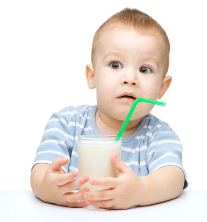 Cute little boy drinks milk using a drinking straw, isolated over whiteの写真素材