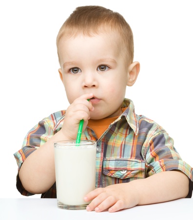 Cute little boy drinks milk using a drinking straw, isolated over whiteの写真素材