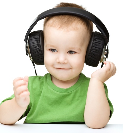 Cute little boy enjoying music using headphones, isolated over whiteの写真素材