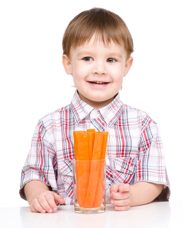 Little boy is eating carrot, isolated over whiteの写真素材