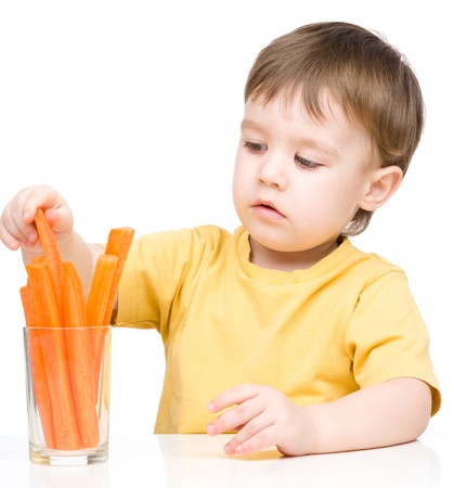 Little boy is eating carrot, isolated over whiteの写真素材