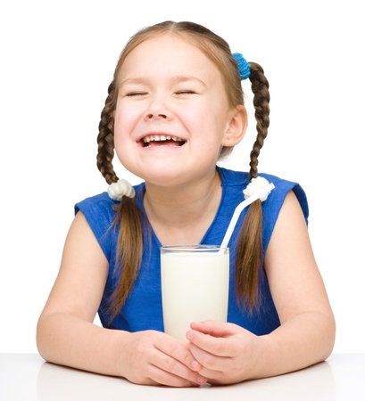 Sad little girl with a glass of milk, isolated over whiteの写真素材