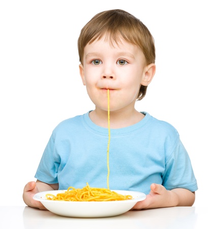 Little boy is sucking up a single spaghetti strand, isolated over whiteの写真素材