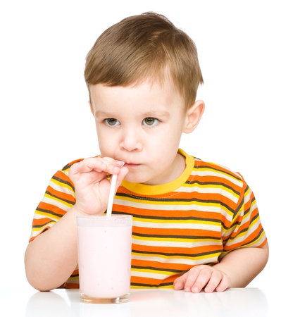 Cute little boy drinks milk using a drinking straw, isolated over whiteの写真素材