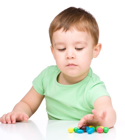 Portrait of a boy with colorful candies, isolated over whiteの写真素材