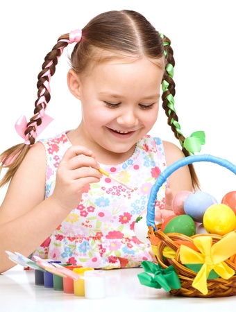 Little girl is painting eggs preparing for Easter, isolated over whiteの写真素材