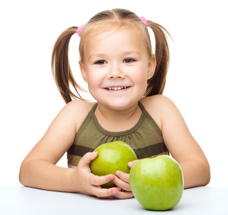 Portrait of a cute cheerful little girl with two green apples, isolated over whiteの写真素材