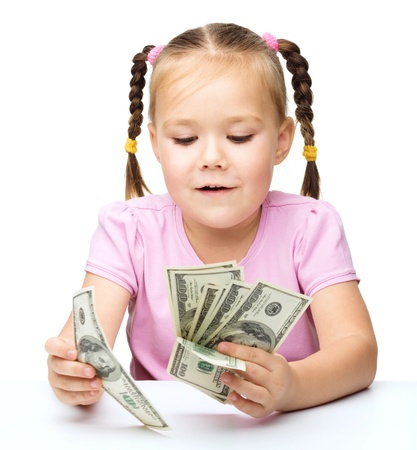 Cute little girl is counting dollars, isolated over whiteの写真素材