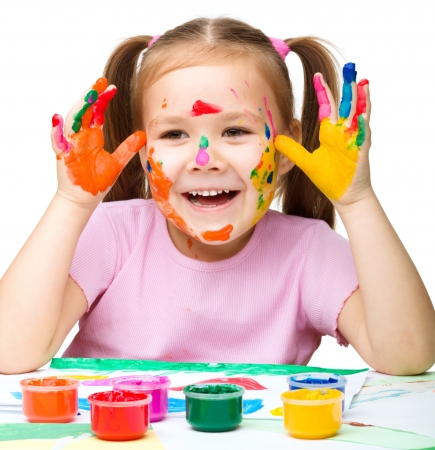 Portrait of a cute cheerful girl playing with paints, isolated over whiteの写真素材