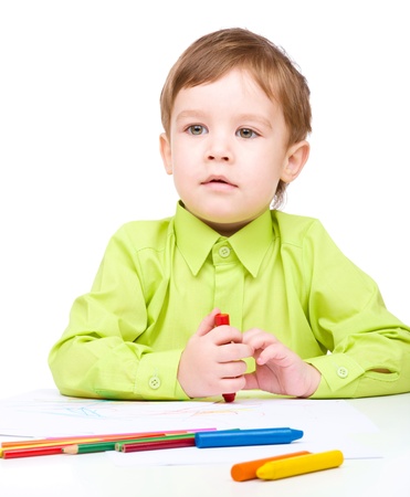 Little boy is drawing using crayon, isolated over whiteの写真素材