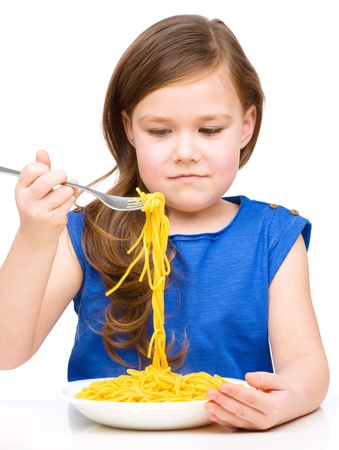 Little girl is eating spaghetti, isolated over whiteの写真素材
