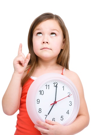 Little girl is holding big clock and pointing up, isolated over whiteの写真素材