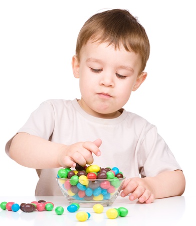 Portrait of a boy with colorful candies, isolated over whiteの写真素材