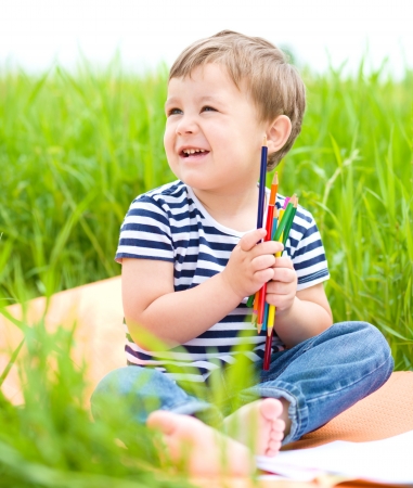 Little boy is playing with pencils outdoorsの写真素材