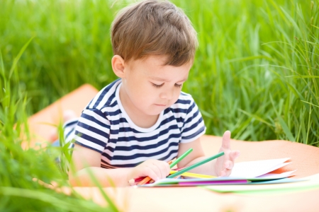 Little boy is playing with pencils outdoorsの写真素材