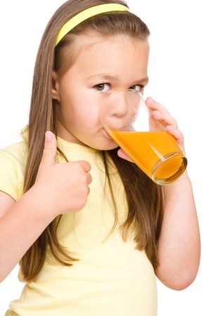 Little girl is drinking orange juice, isolated over whiteの写真素材