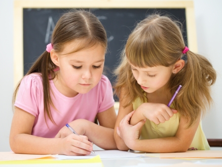 Cute little girls are writing using a pen in preschoolの写真素材