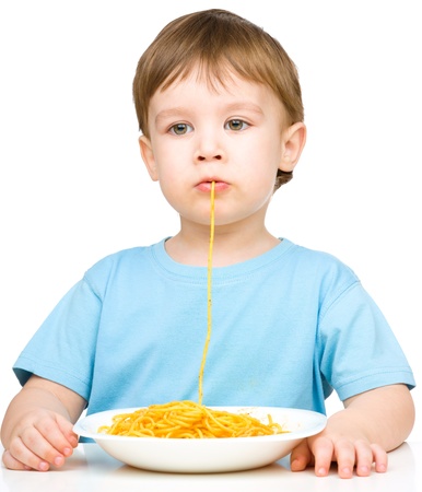 Little boy is sucking up a single spaghetti strand, isolated over whiteの写真素材