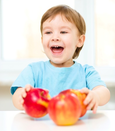 Portrait of a happy little boy with red applesの写真素材