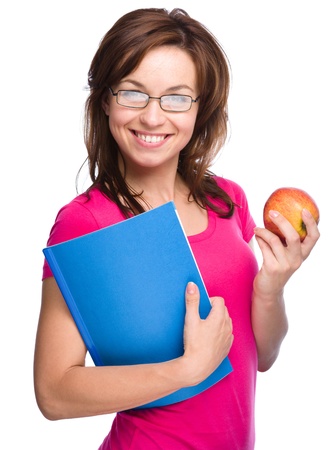 Young skinny student girl is holding exercise book and apple, isolated over whiteの写真素材