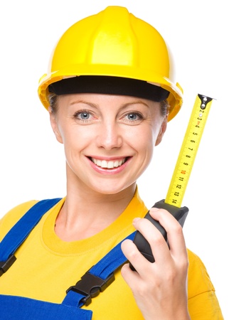 Young happy lady as a construction worker with tape measure, isolated over whiteの写真素材