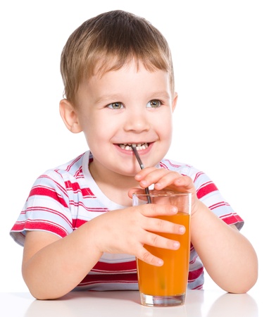 Little boy is drinking carrot juice using straw, isolated over whiteの写真素材