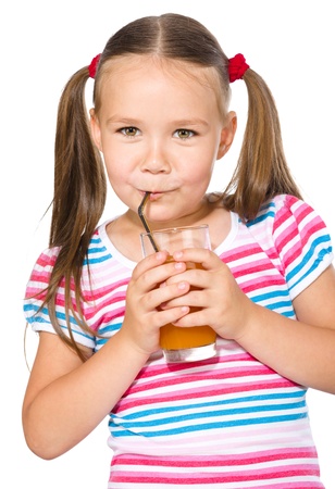 Little girl is drinking carrot juice using straw, isolated over whiteの写真素材