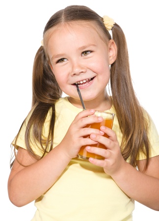 Little girl is drinking carrot juice using straw, isolated over whiteの写真素材