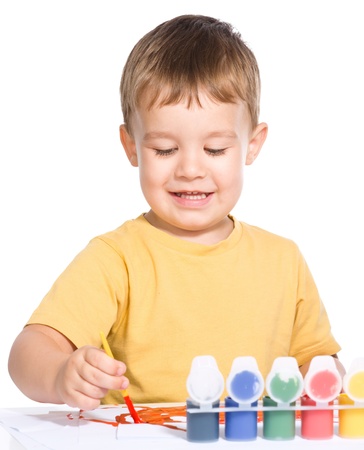 Portrait of a cute little boy playing with paints, isolated over whiteの写真素材