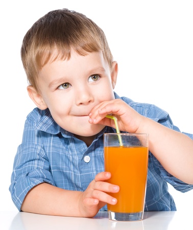 Little boy is drinking carrot juice using straw, isolated over whiteの写真素材