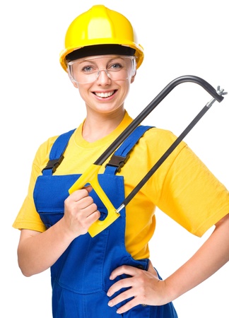 Young happy lady as a construction worker with hacksaw, isolated over whiteの写真素材