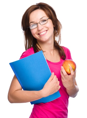 Young student girl is holding exercise book and apple, isolated over whiteの写真素材