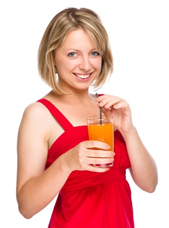 Young woman is drinking carrot juice using straw, isolated over whiteの写真素材