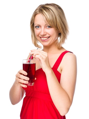 Young woman is drinking cherry juice using straw, isolated over whiteの写真素材
