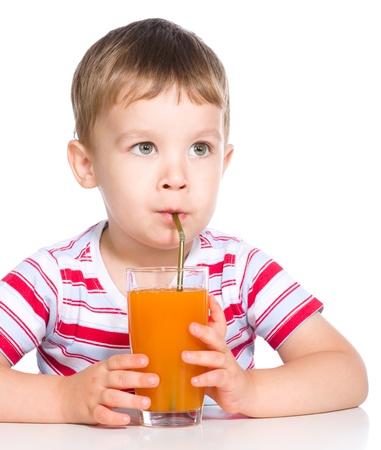 Little boy is drinking carrot juice using straw, isolated over whiteの写真素材